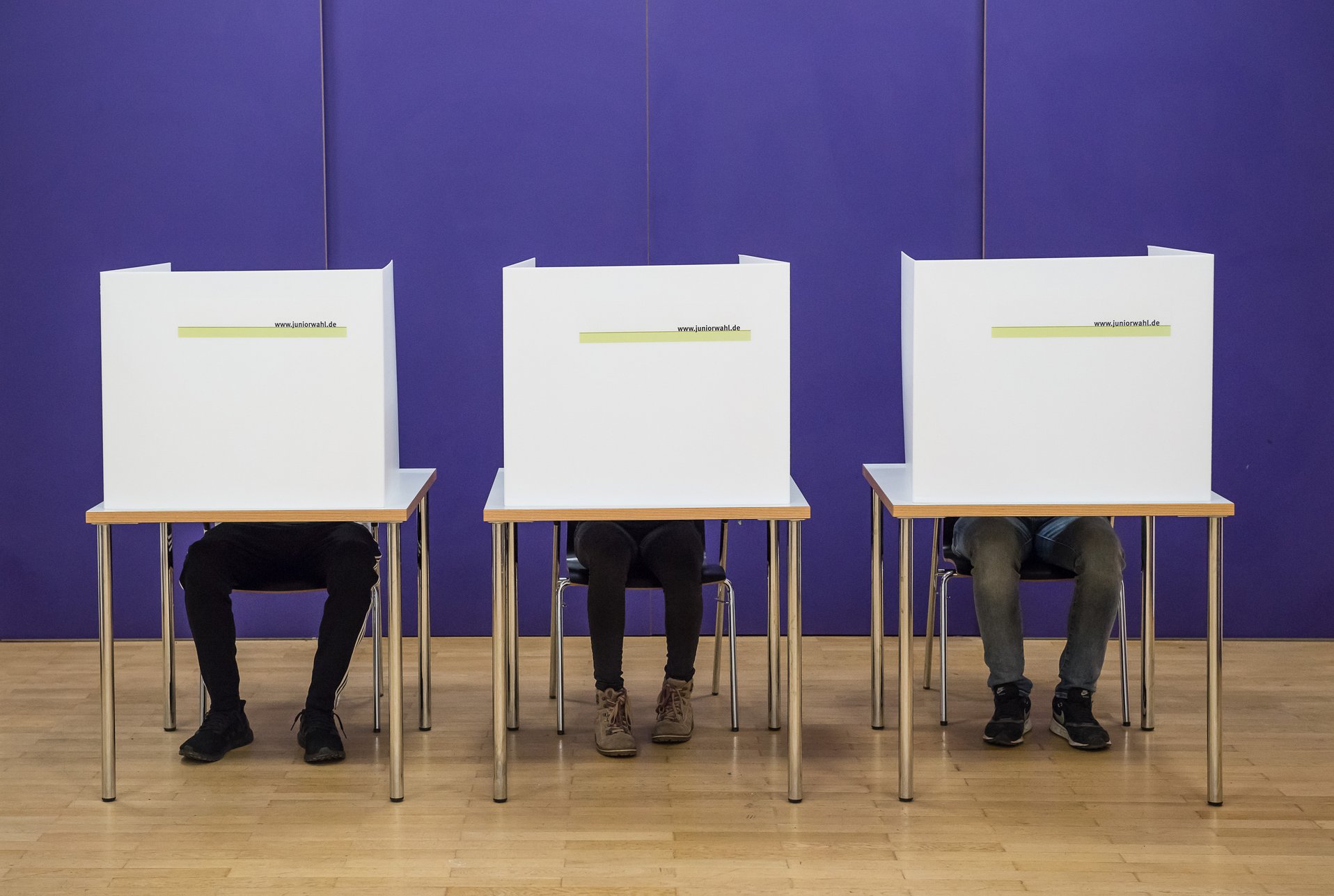 drei Wähler*innen verborgen hinter Wahlkabinen